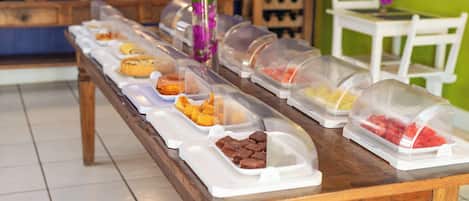 En buffet med forskellige retter, dækket til med gennemsigtige plastbeholdere.