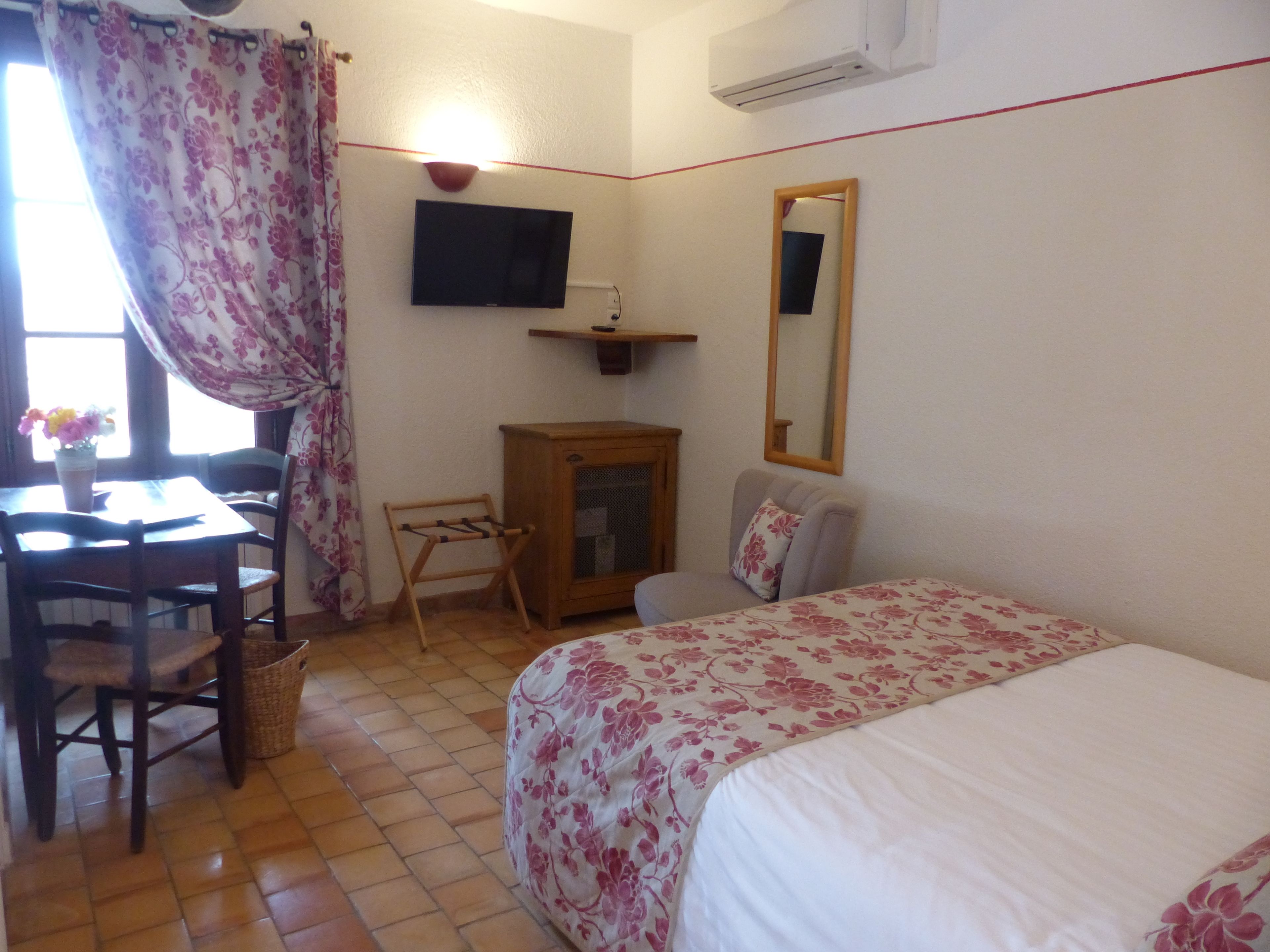 A bedroom with a bed, a desk, a chair, a television, and a mirror.