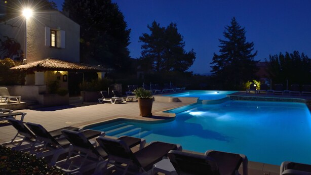 A swimming pool with lounge chairs and a building with a tiled roof. - Hotel Charembeau (Forcalquier)