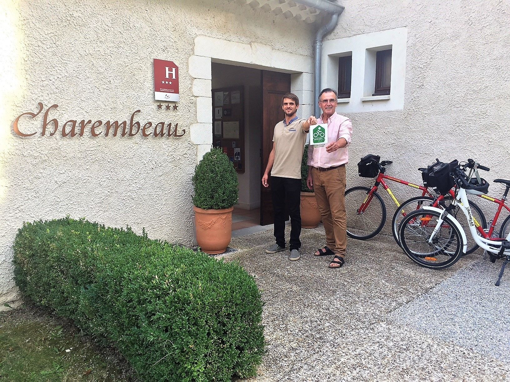 A hotel entrance with a sign reading "Charmesbeau" and a rating of 4 stars. There are two bicycles parked outside.