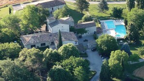 An aerial view of a property with multiple buildings, a swimming pool, and surrounding greenery. - Hotel Charembeau (Forcalquier)