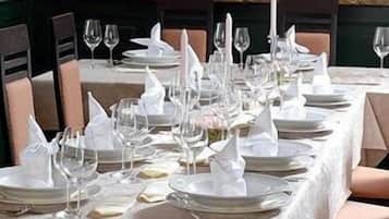 A formal dining table set with white tablecloths, plates, glasses, and napkins.
