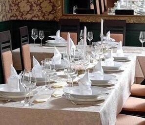 A formal dining table set with white tablecloths, plates, glasses, and napkins. - U Pramenu (Plzen)