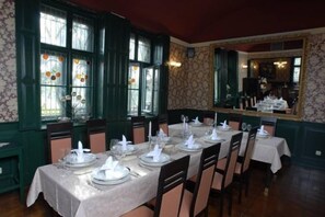 A dining area with tables set for service, large windows with decorative elements, and a mirror on the wall. - U Pramenu (Plzen)