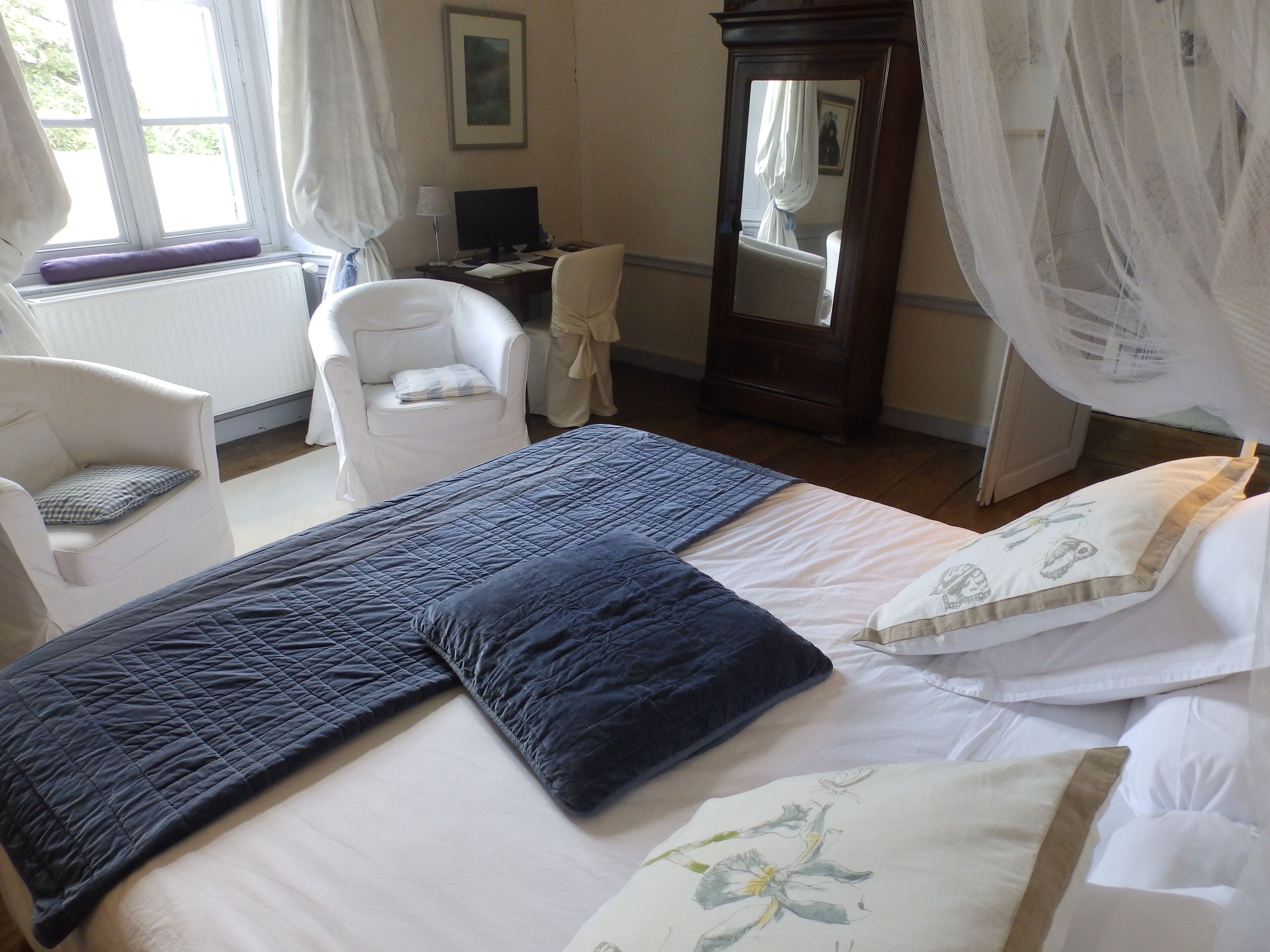 Un dormitorio con cama, una silla, un escritorio y una computadora.
