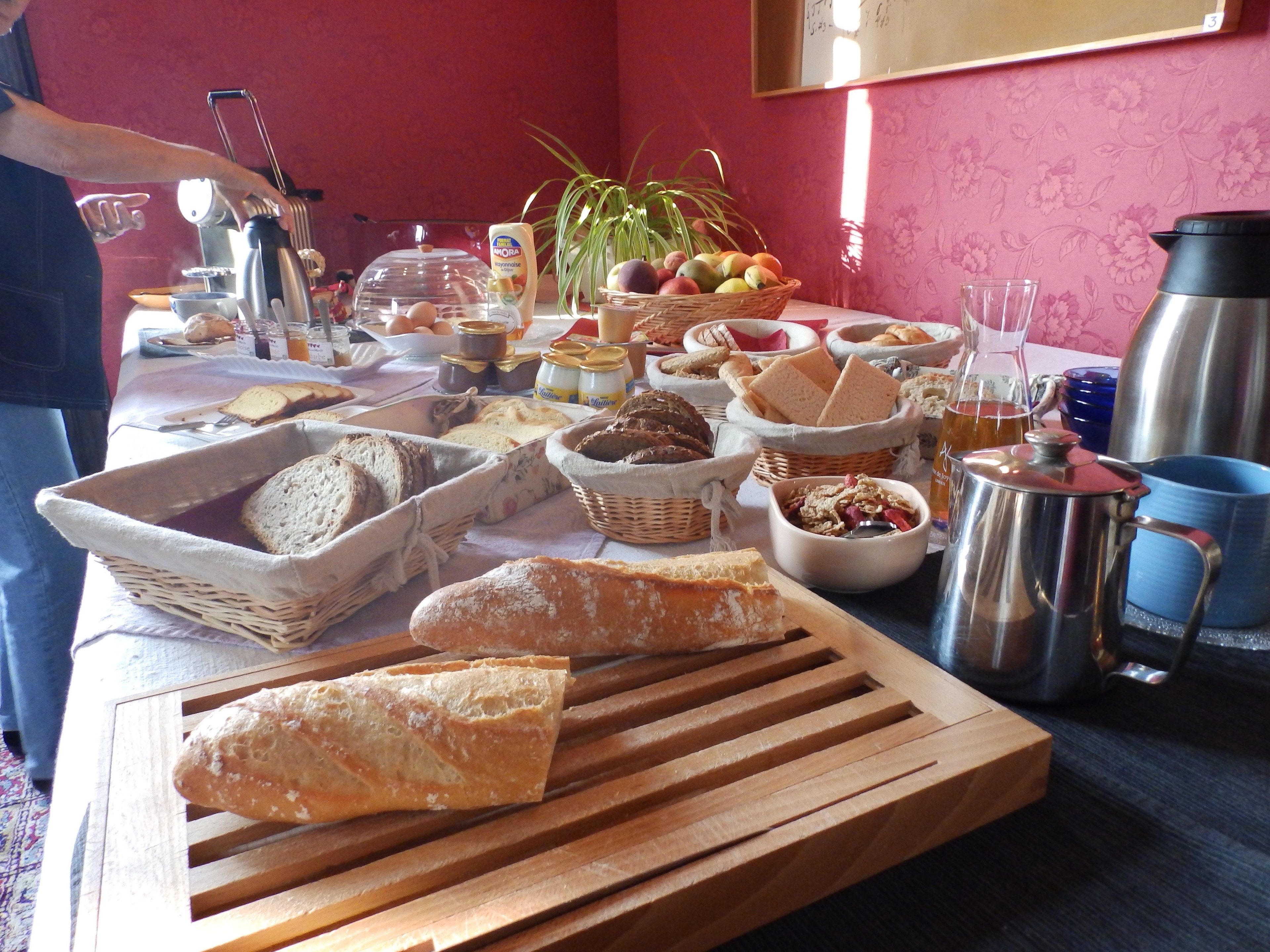 A breakfast buffet with various breads, fruits, and beverages.