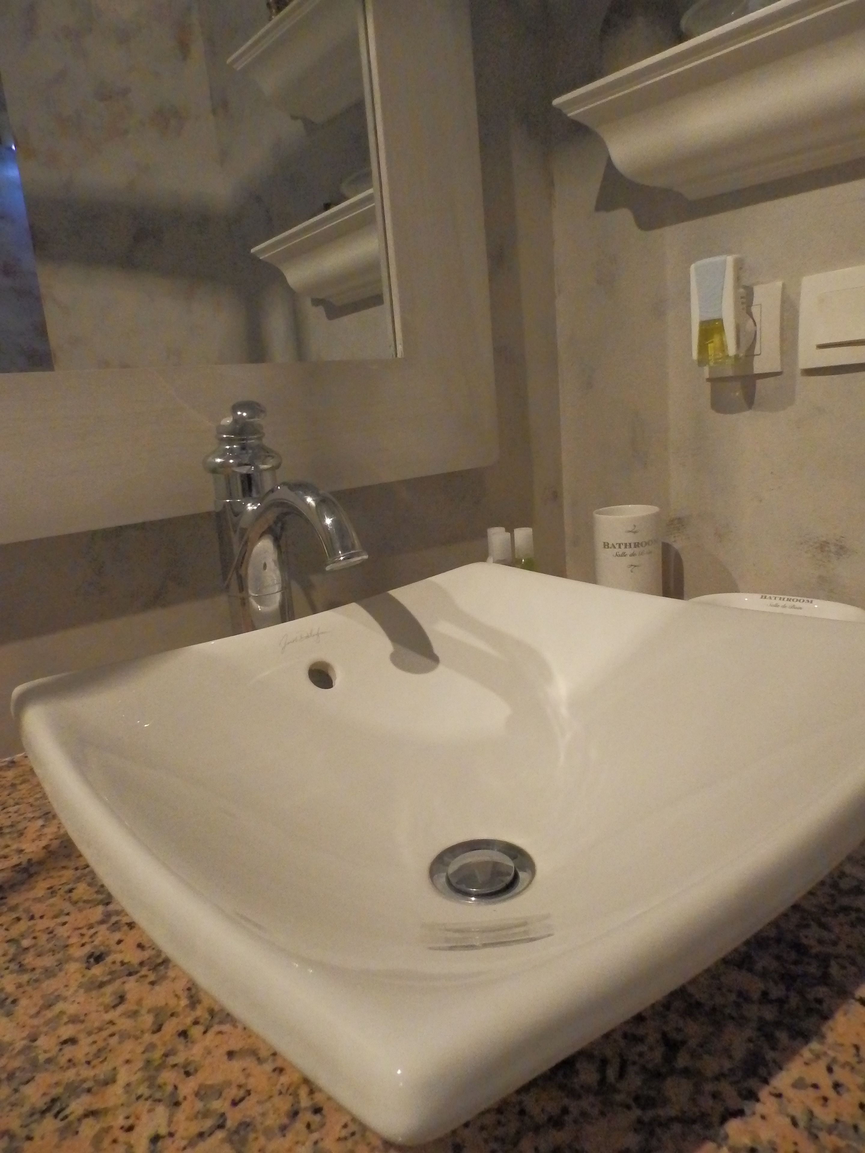 Un baño con lavamanos blanco, un espejo y un dispensador de toallas.