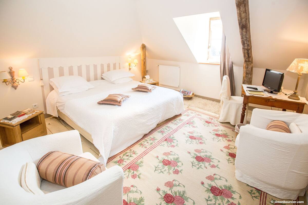 Une chambre à coucher comprenant un lit, des tables de chevet, un bureau avec un ordinateur et une chaise.