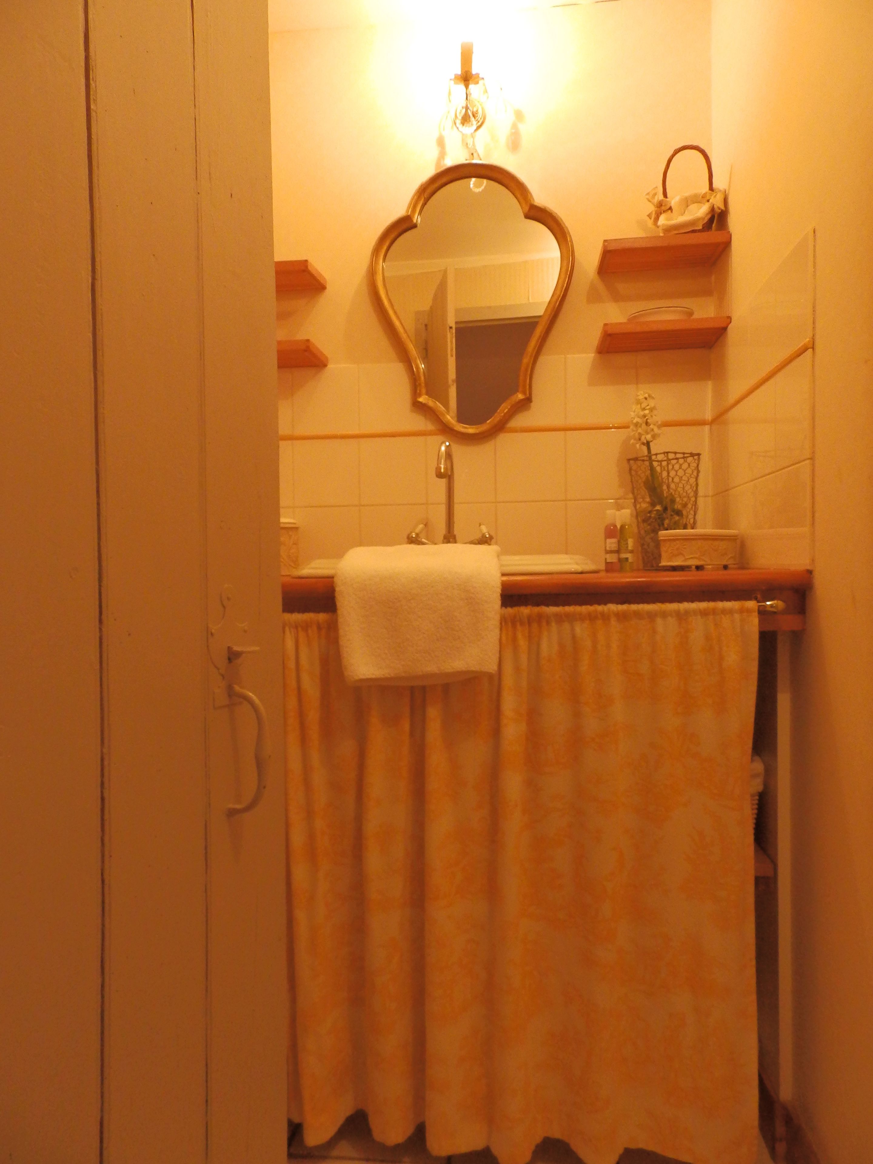 Un bagno con lavandino, specchio, asciugamano e un piccolo ripiano con articoli da toilette.
