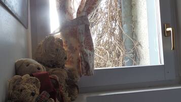 A window with a floral curtain, a teddy bear, and a door with a brass handle.