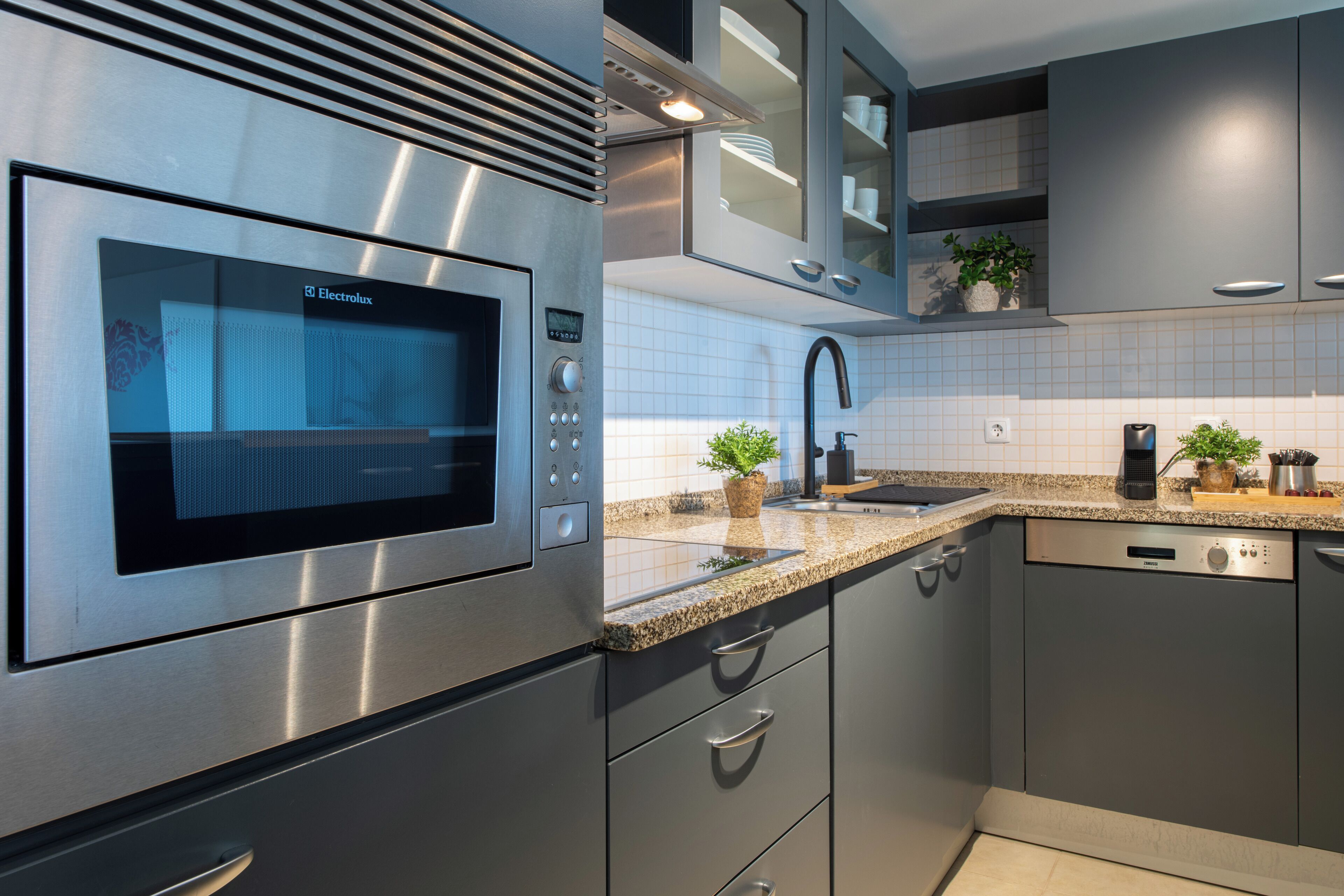 A modern kitchen with stainless steel appliances, granite countertops, and built-in cabinetry.