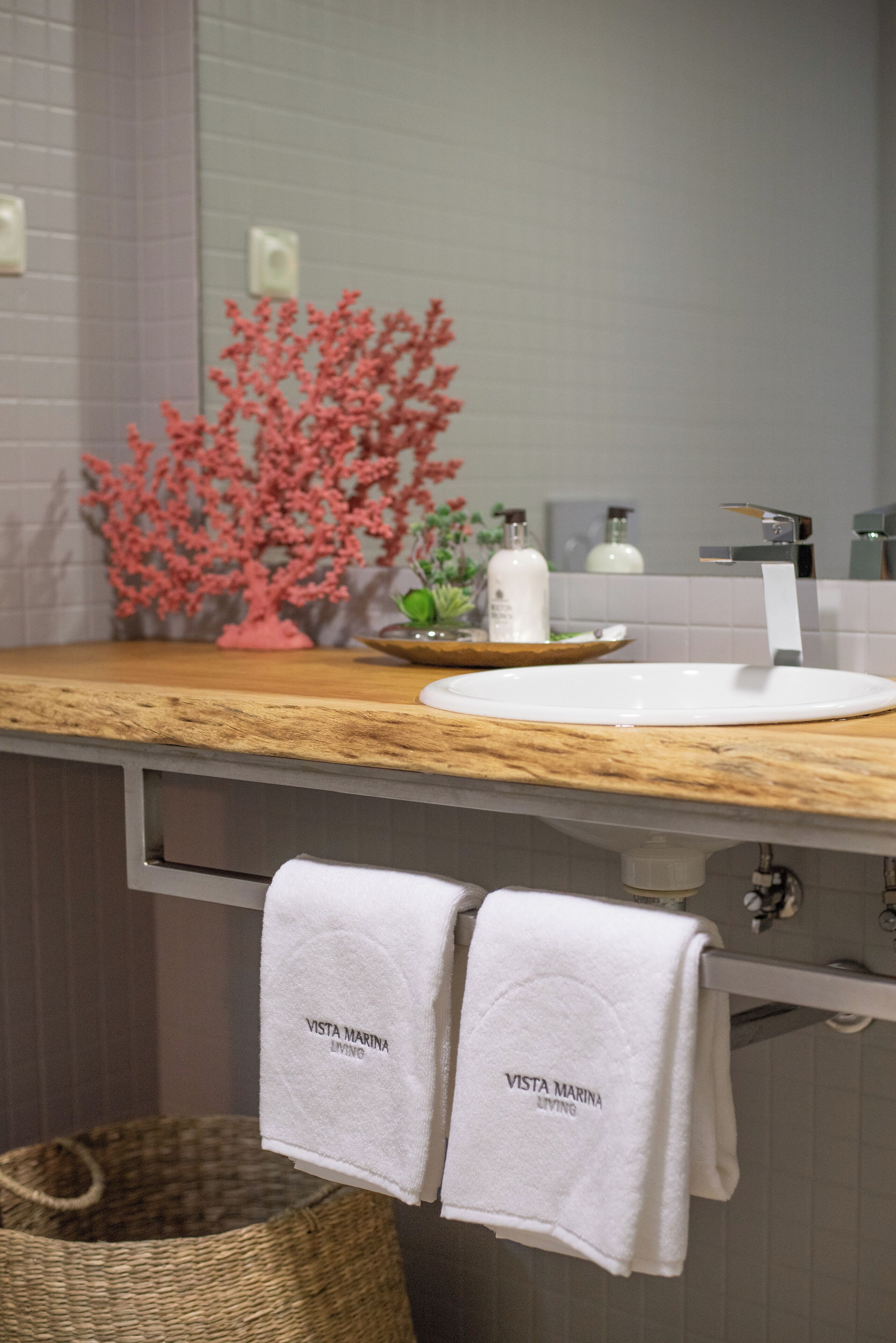A bathroom with a wooden countertop, a white sink, and two towels hanging from a rack.
