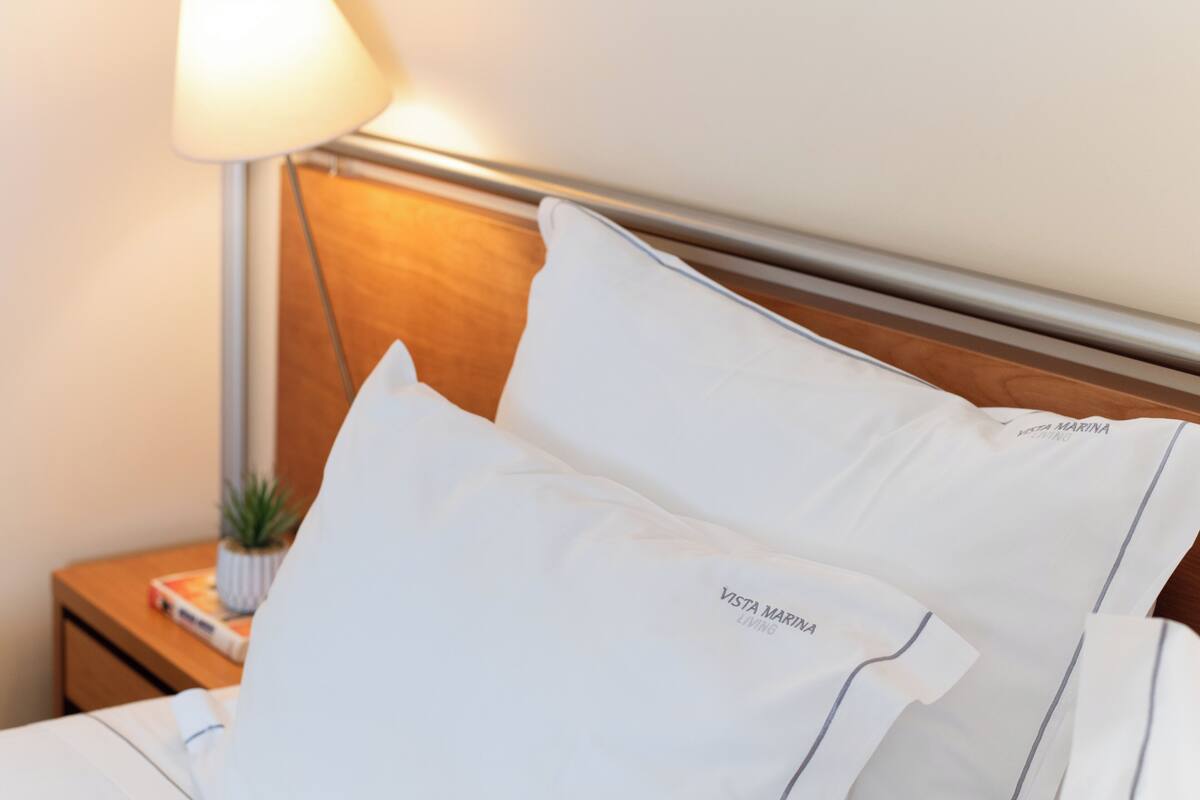 A neatly made bed with white pillows and a headboard.