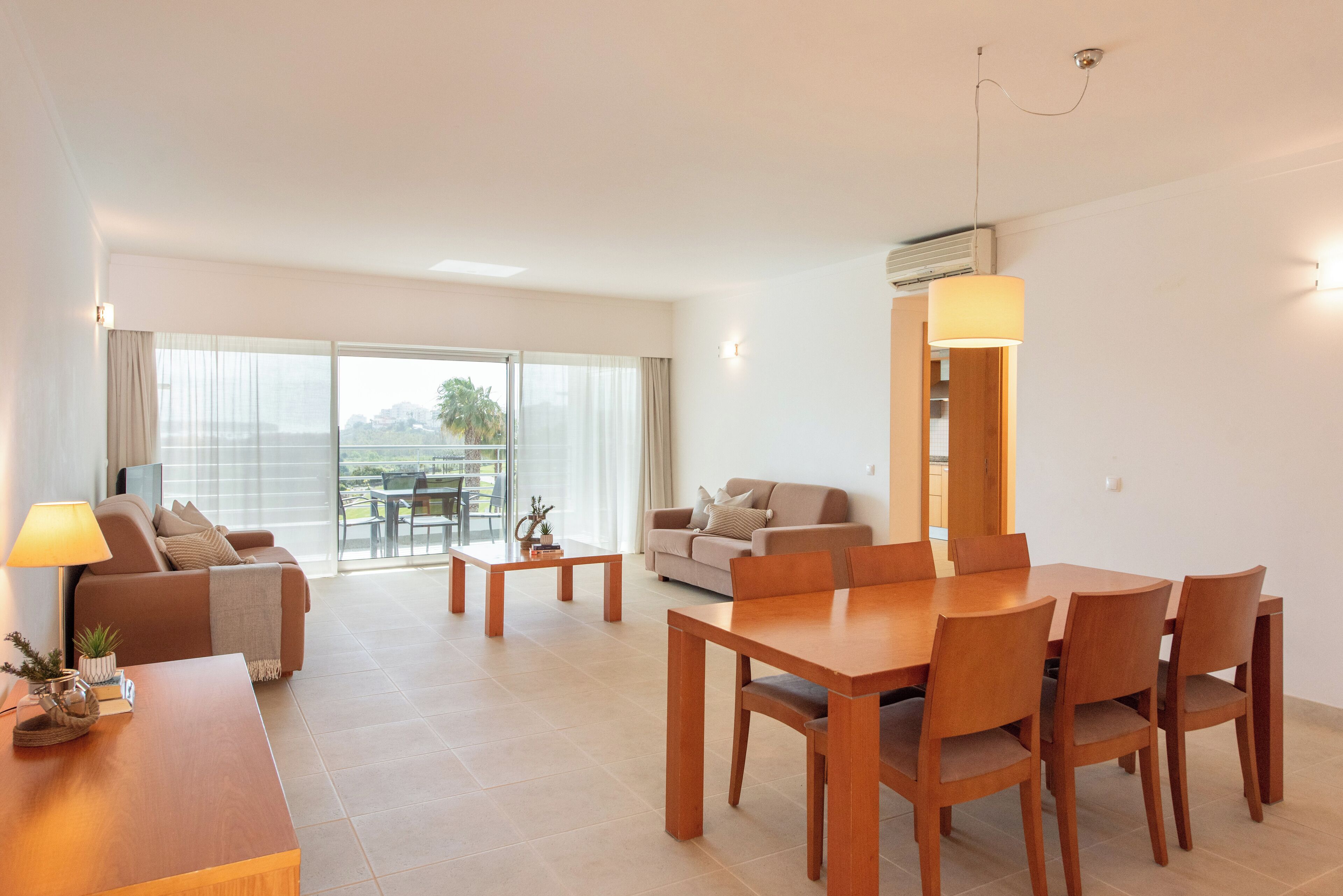 Una sala de estar moderna con comedor, un sofá, una mesa de centro y vistas al exterior.