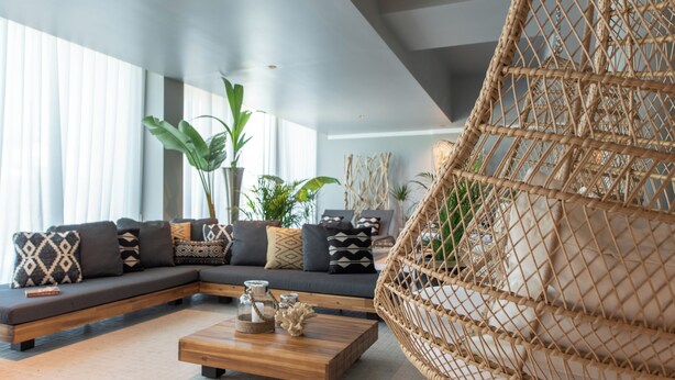 Una sala de estar moderna con un sofá modular, una mesa de centro de madera y un sillón colgante.
