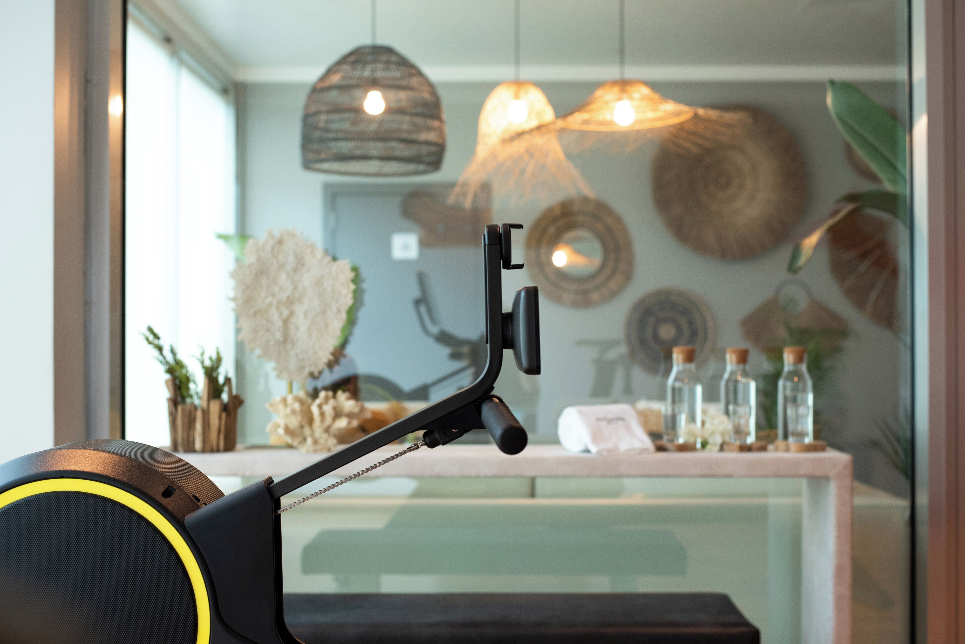A stationary exercise bike with a headrest and handlebars, positioned in front of a glass window.