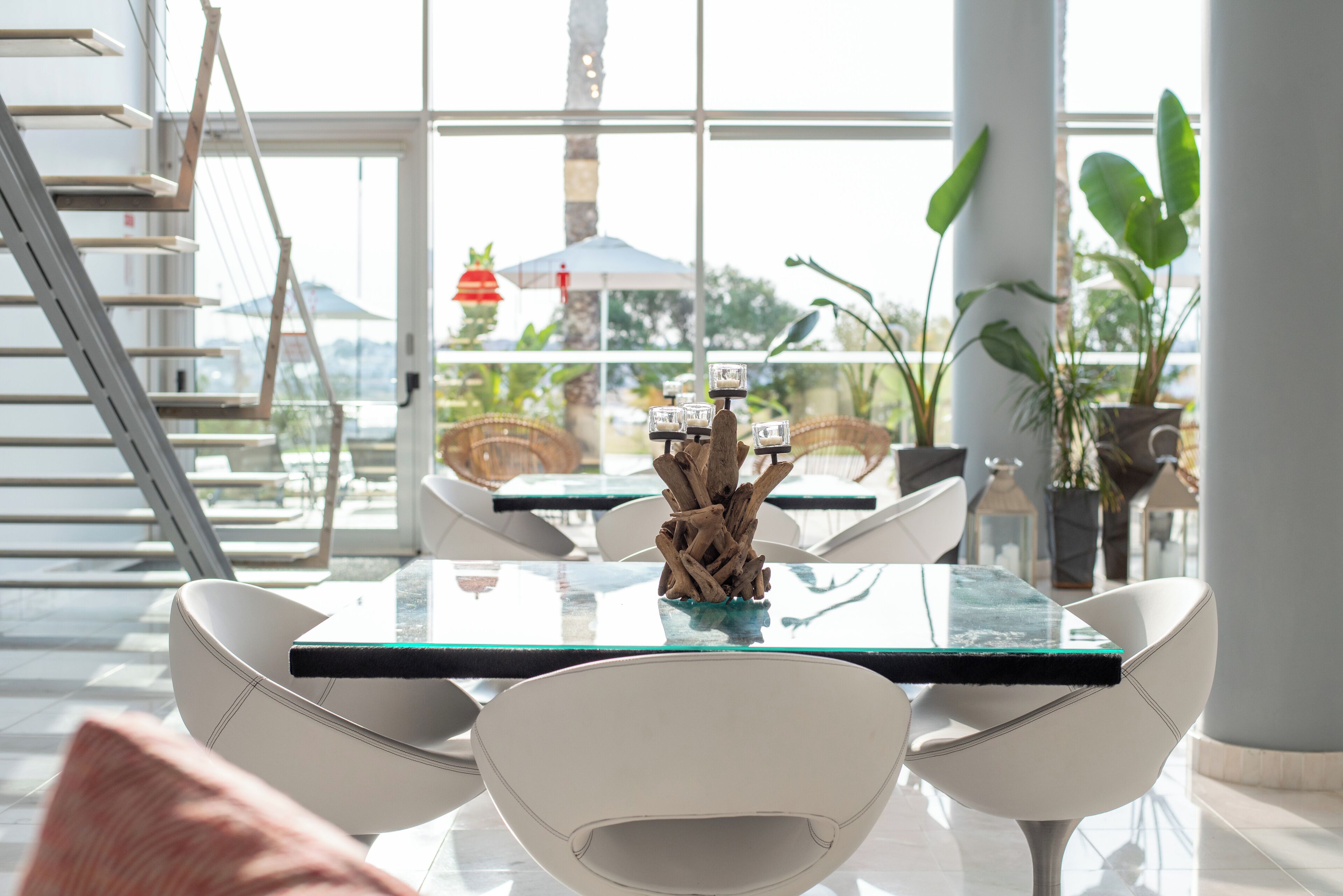 A modern dining area with a glass-top table, white chairs, and a decorative centerpiece.