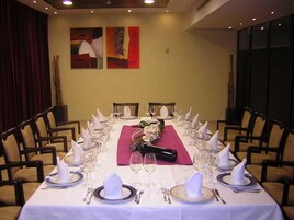 Un salón de conferencias con una larga mesa dispuesta para un evento formal, rodeado de sillas.