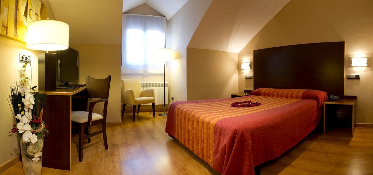 Une chambre d’hôtel avec un grand lit, un bureau avec une chaise, une télévision et une lampe.