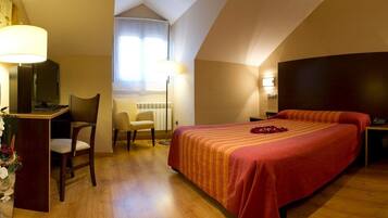 Une chambre d’hôtel avec un grand lit, un bureau avec une chaise, une télévision et une lampe.