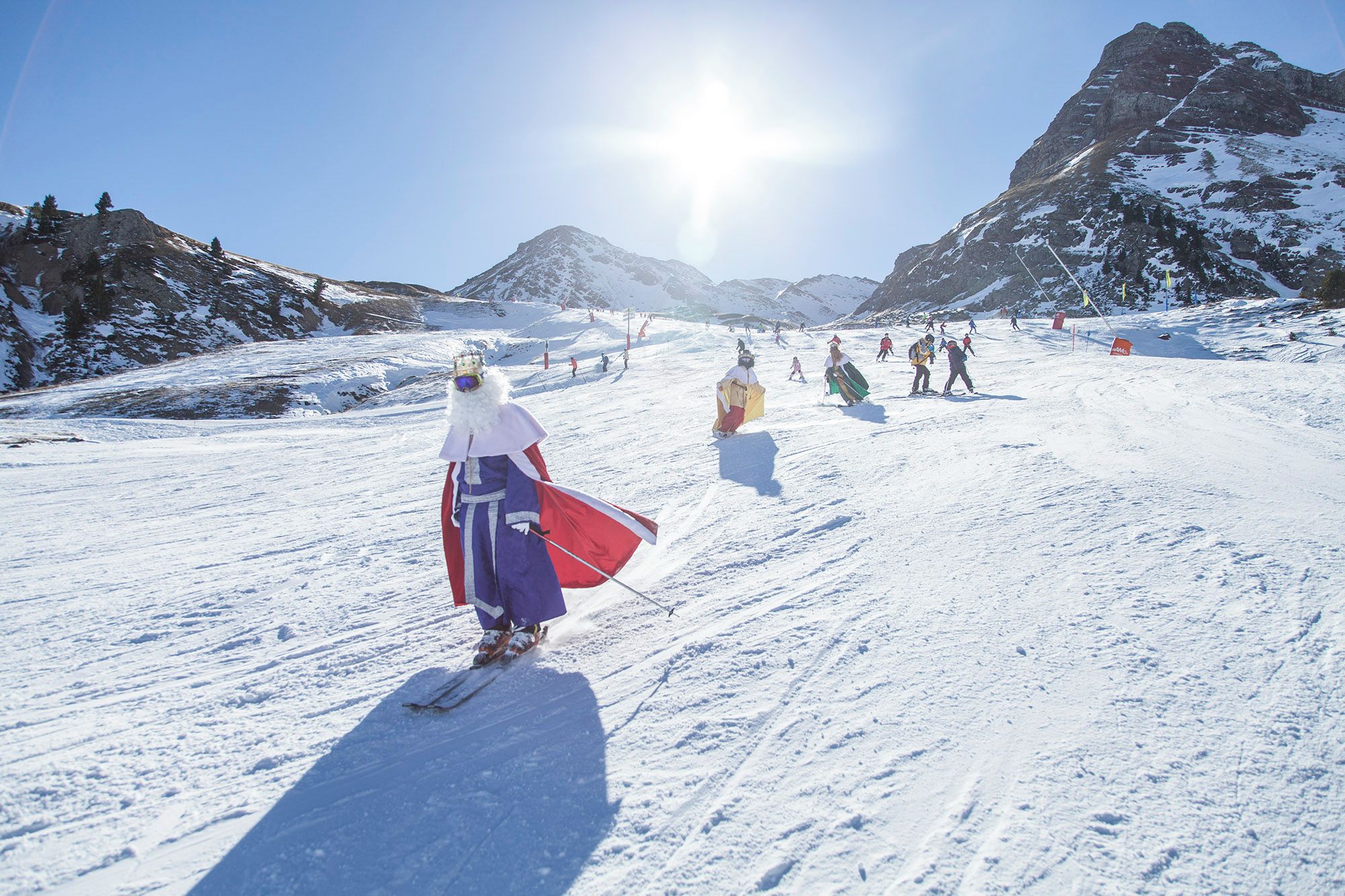 Eine Skipiste mit Skifahrern und einer Person in traditioneller Tracht.