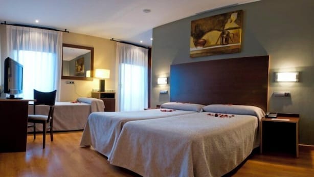 Une chambre d’hôtel avec deux lits, un bureau, une chaise et un tableau au mur.