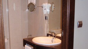 Ein Badezimmer mit Waschbecken, Toilette, Fön und Spiegel.