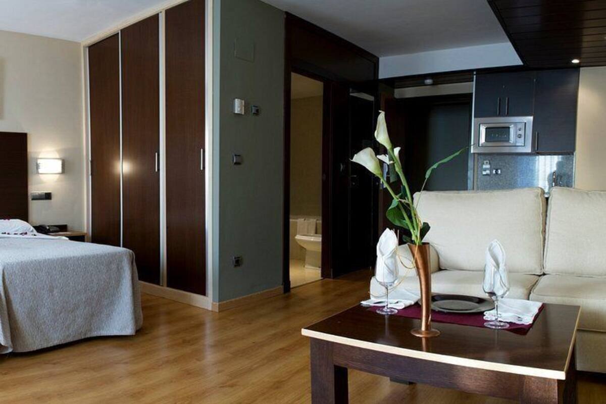 Une chambre d’hôtel avec un lit double, un canapé, une table à manger et un coin cuisine.