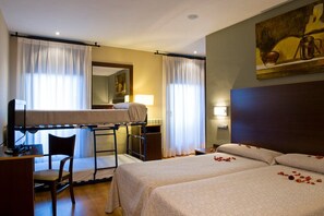 A hotel room with bunk beds, a desk, a chair, and a bed with rose petals. - Snö Ciudad de Sabiñanigo (Sabinanigo)
