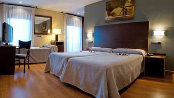 A hotel room with two beds, a desk, a chair, and a painting on the wall.