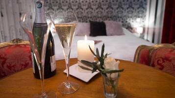 Une table avec une bouteille de vin, un verre de vin, une bougie et un vase avec une fleur.