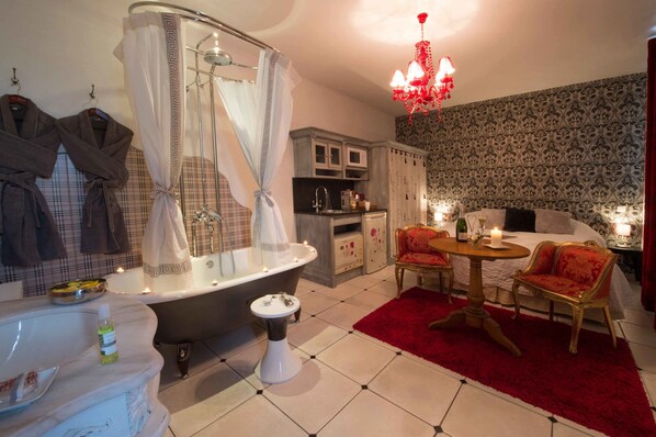 A bathroom with a bathtub, a sink, and a toilet. There is a vanity with a mirror and a towel rack.