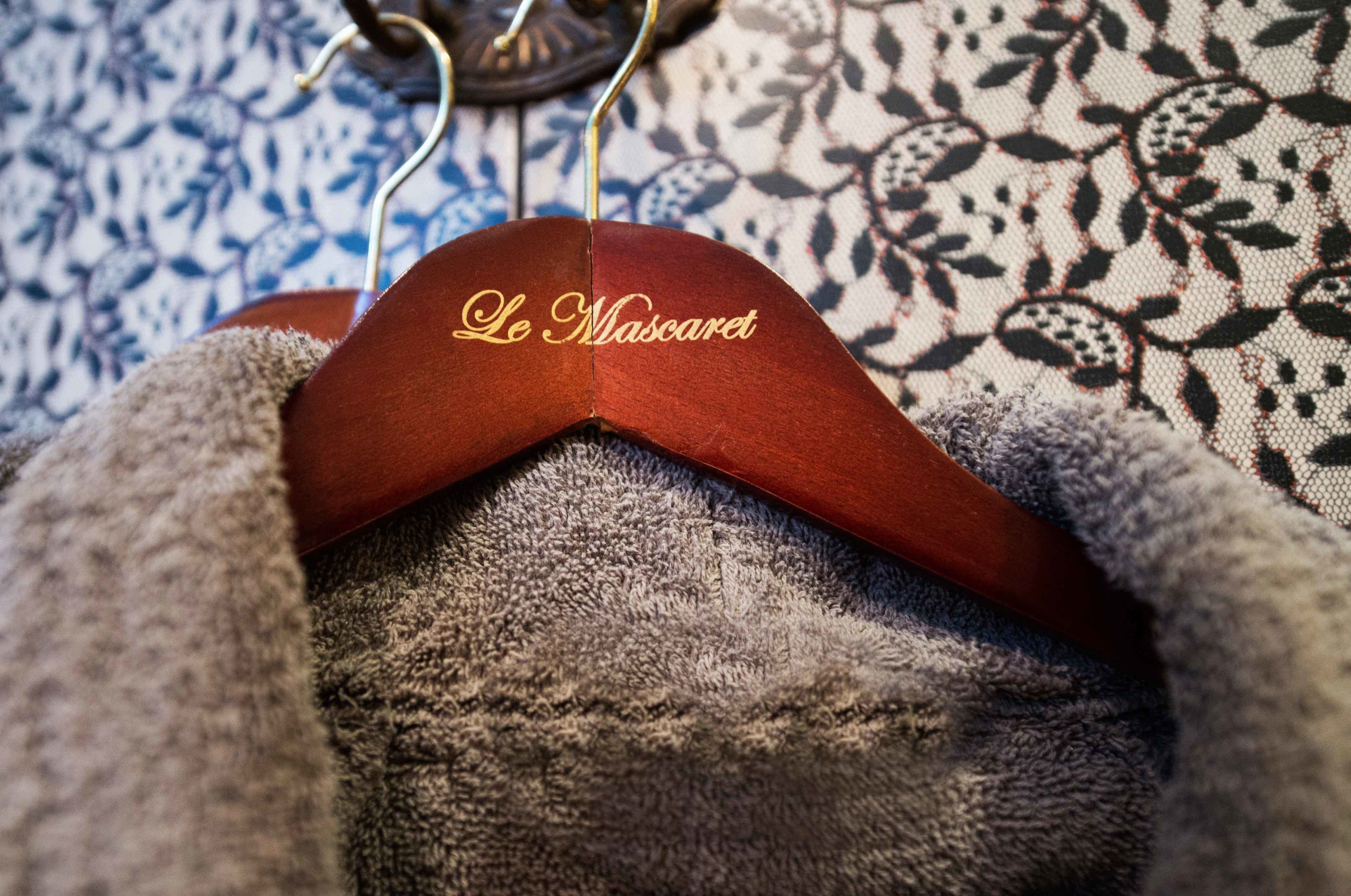Um cabide com a inscrição "Le Mascaret" sobre um fundo de tecido estampado.