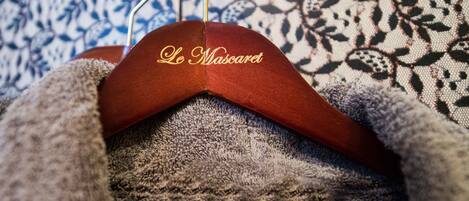 A hanger with the text "Le Mascaret" on it, placed on a patterned fabric background.