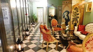 A checkered floor, a red and gold chair, a white sofa, and a painting of a woman. - Le Mascaret (Blainville-sur-Mer)