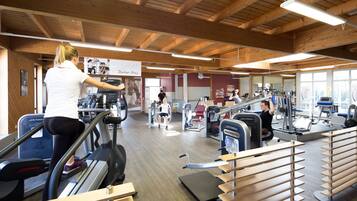 Un gimnasio con cintas de correr, equipamiento de ejercicio y techo de madera.