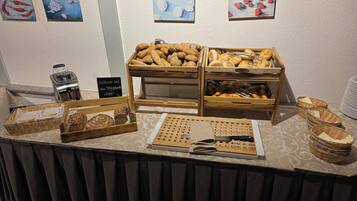 A buffet table with various food items, including bread, pastries, and a toaster.