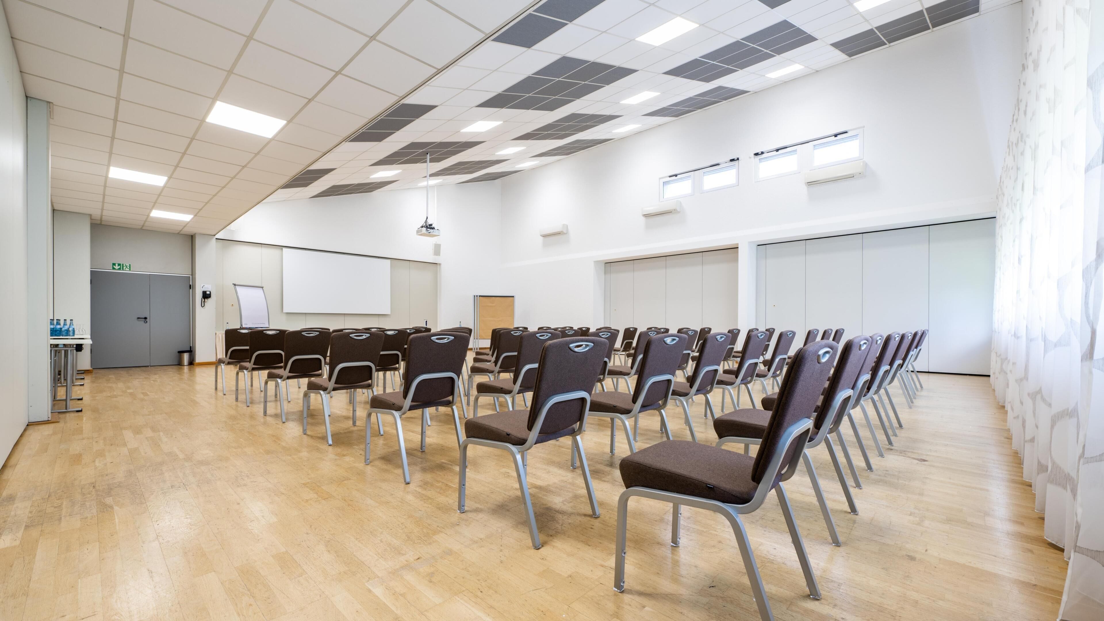 A conference room with rows of chairs, a whiteboard, and a projector.