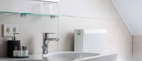 Un baño moderno con un espejo grande, dos lavamanos y un estante de vidrio.
