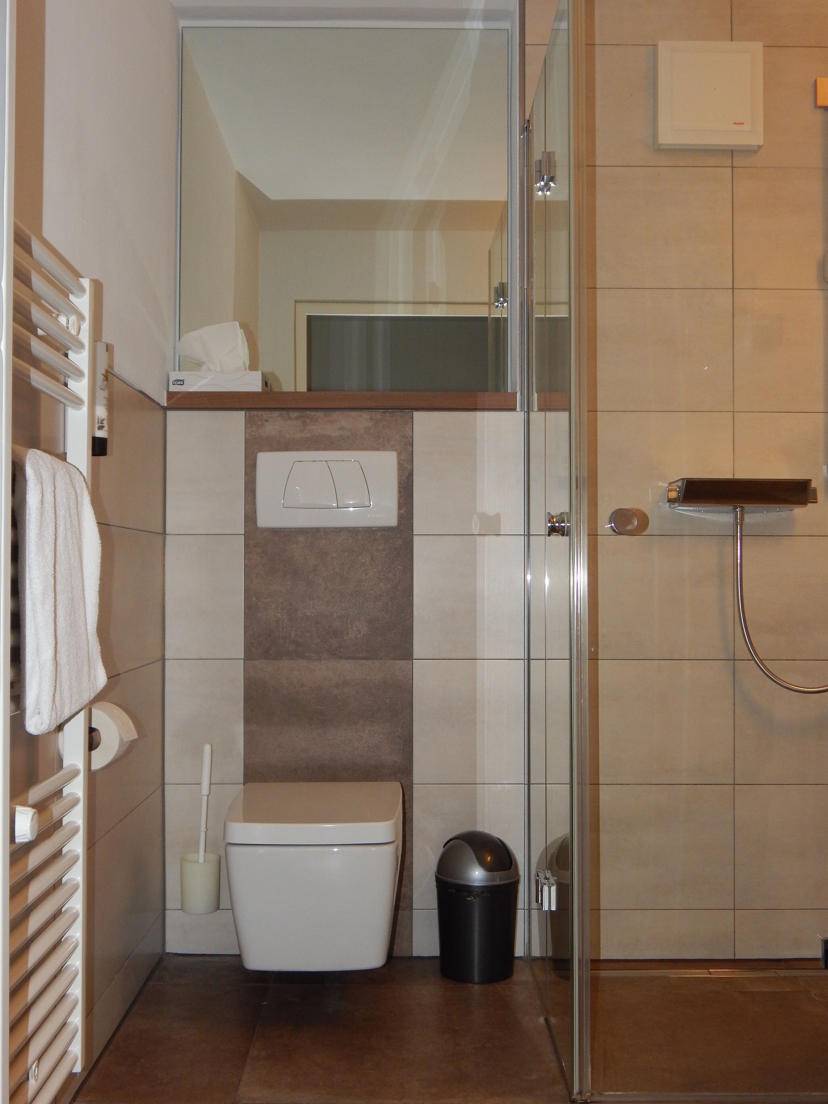Et lille badeværelse med toilet, bidét og bruser.