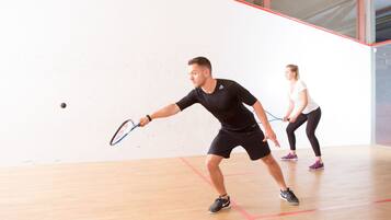 Un court de squash doté d’un plancher en bois et de lignes de démarcation rouges.