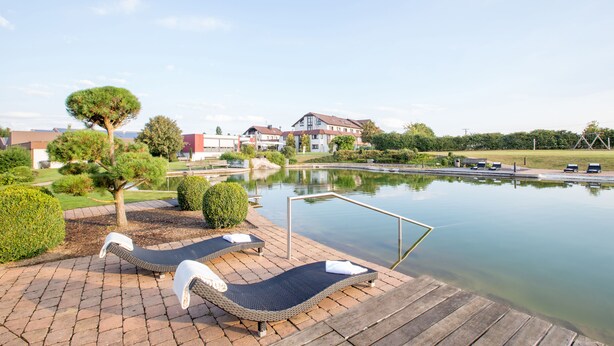 A poolside area with lounge chairs and a wooden deck. - ARAMIS Tagungs- und Sporthotel (Gaeufelden)