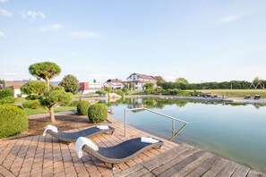 A poolside area with lounge chairs and a wooden deck. - ARAMIS Tagungs- und Sporthotel (Gaeufelden)