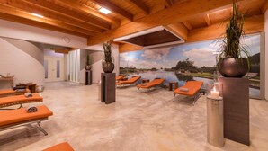 A spa area with sun loungers, a mural of a lake, and wooden ceiling beams. - ARAMIS Tagungs- und Sporthotel (Gaeufelden)