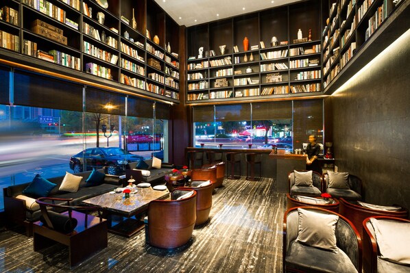 A modern library with bookshelves, seating, and a view of the street.