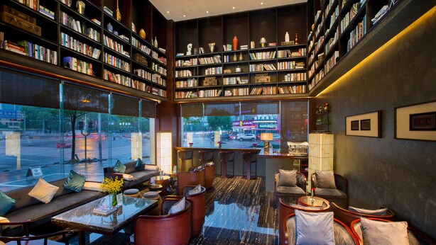 Un intérieur moderne avec un coin salon, des étagères et une vue sur la rue.