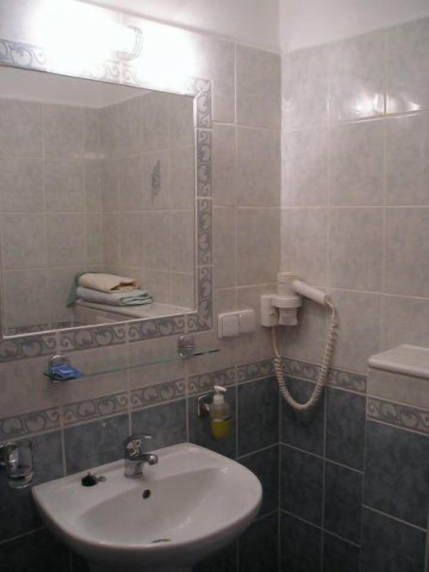 A bathroom with a sink, mirror, and a telephone.