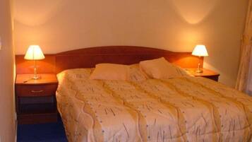 A neatly made bed with a patterned bedspread, two bedside lamps, and a wooden headboard.