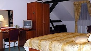 A hotel room with a bed, a desk with a television, a wardrobe, and a chair.
