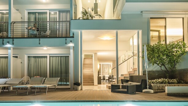 A modern two-story building with a swimming pool, outdoor seating, and a balcony with a railing. - Villa Katy (Bardolino)
